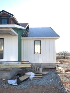 White board and batten smart siding with black metal roof